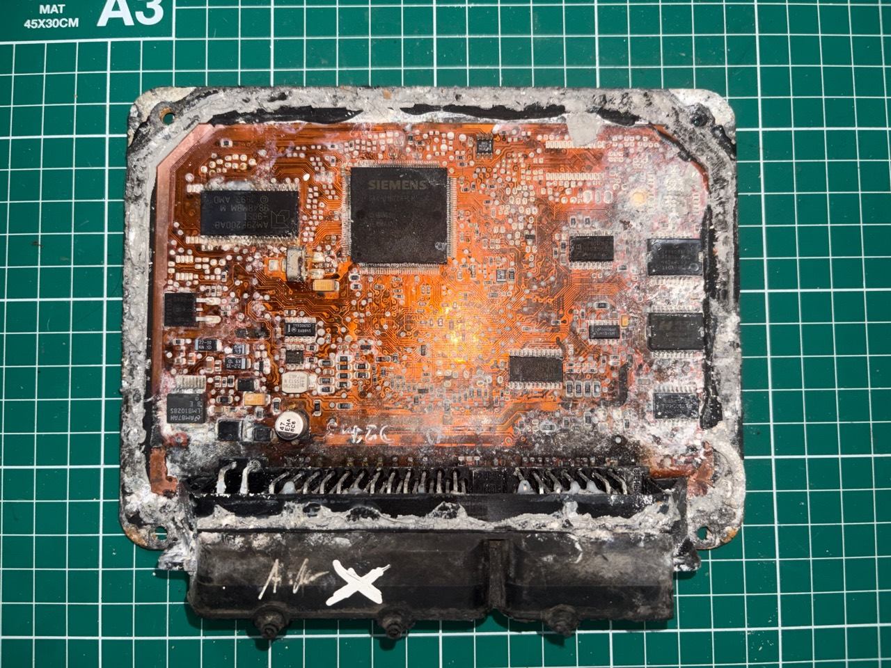 Corroded water damaged ECU circuit board on bench